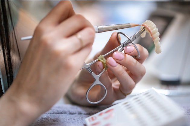 Technician matching shade against a ceramic bridge