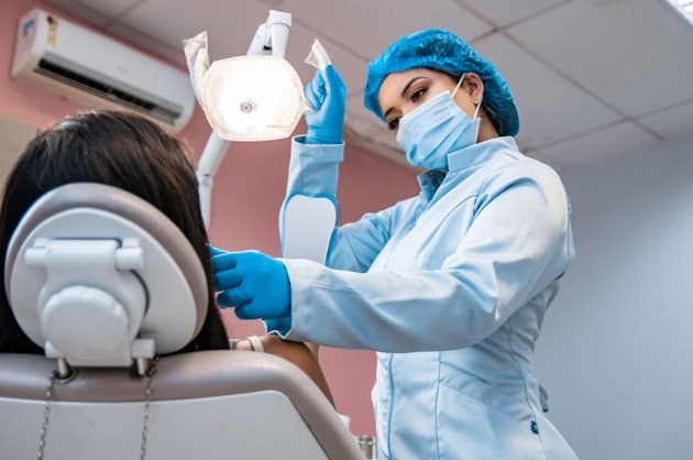 Dentist positioning the operating light over a patient in the chair